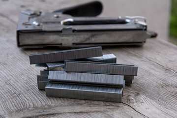 Close-up of a staples and staple gun on a wooden board
