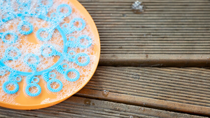 Children blow bubbles in the park. A bowl with soap bubbles close-up. Exciting outdoor activities for children.