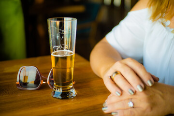 concepto de paz y tranquilidad de una mujer sentada en la mesa de un bar con una cerveza y las gafas de sol sobre la mesa