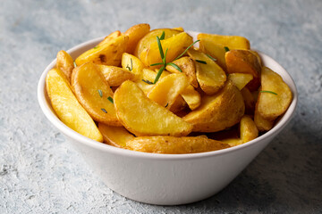 Roasted potato wedges with herbs and sea salt on plate, top view (Turkish name; elma dilim patates)