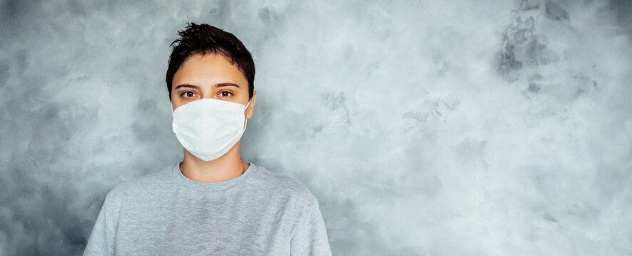 the third wave of the coronavirus. indian strain. girl with short hair in a medical mask on a gray background