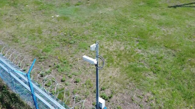 A video surveillance camera with a searchlight is installed on the protected perimeter. Protected area. Blue fence. All-round overview. Drone video.