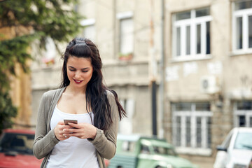 Fototapeta premium Young cute female using smartphone on the street.