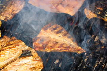 Grilled mackerel fish with smoke on a charcoal barbecue grill.