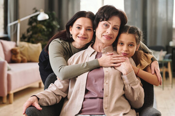 Affectionate females of three generations standing in front of camera