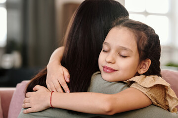 Obraz na płótnie Canvas Smiling little girl embracing her mother at home