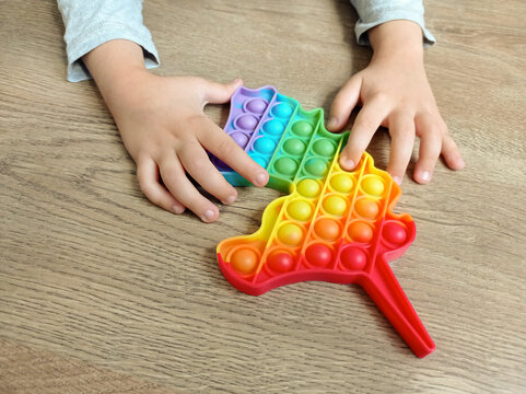 Pop It Toy. The Child's Hands Press On The Pop It Toy In The Shape Of A Rainbow Unicorn