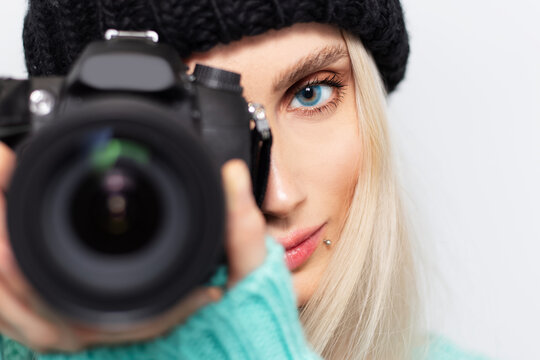 Close-up portrait of blonde girl photographer taking photo on DSLR camera.