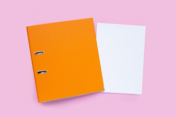 Office folder with paper on pink background. Top view