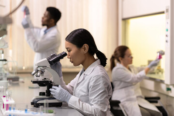 Fototapeta na wymiar Chinese female scientist looking in microscope in laboratory