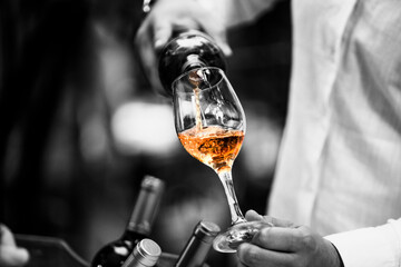 The waiter serves rose, red and white wine from the wine bottle in the wine glass at an event. - 440413369