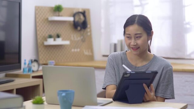 Young businesswoman sitting and using digital tablet learning and studying graph for her finance while using chart for stock marketing working at home office