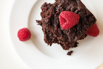 Overhead of stack of dark chocolate raspberry brownies  on a white plate against light background