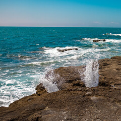 water spraying through the rocks on the coast