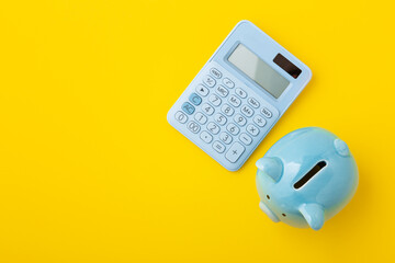 Piggy bank with calculator on yellow background - obrazy, fototapety, plakaty