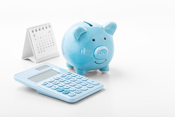 Piggy bank with blue calculator and calendar on white background - obrazy, fototapety, plakaty