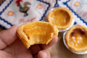 Man's hand with a close-up of some typical Portuguese cream cakes.