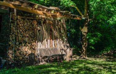 An old wooden bench on the background of firewood in an overgrown garden.