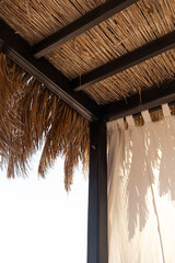 Fototapeta na wymiar Beautiful lounge pavilion canopy for relax on the beach with sea side view and blue sky. Tent made of dry palm leaves