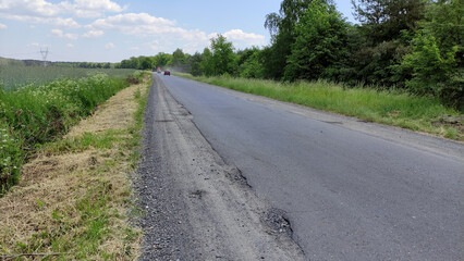 Fototapeta na wymiar Stara, zniszczona droga lokalna.