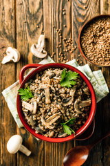 buckwheat porridge with mushrooms in a ceramic pot on a wooden background