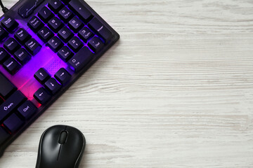 Modern RGB keyboard and mouse on white wooden table, flat lay. Space for text