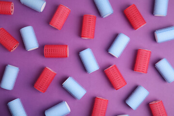 Hair curlers on purple background, flat lay. Styling tool