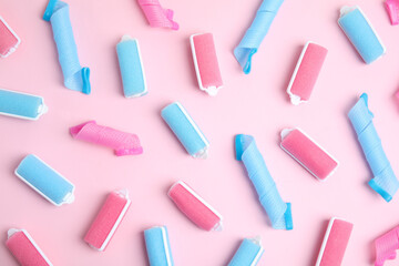 Different hair curlers on pink background, flat lay. Styling tool
