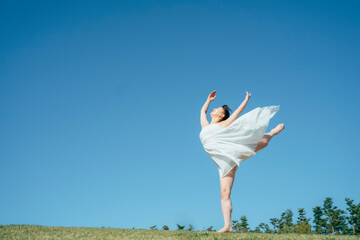Fototapeta premium 空と白いワンピースの踊る女性（ジャンプ） 