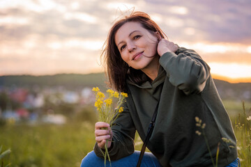 Portrait of a woman traveling on a summer evening against backdrop of landscape and sunset.