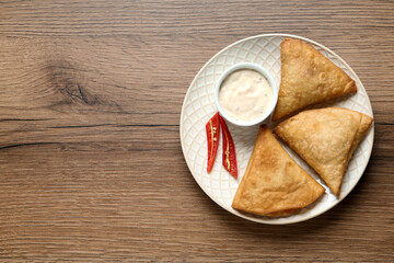 Fototapeta na wymiar Fresh delicious crispy samosas served on wooden table, top view. Space for text