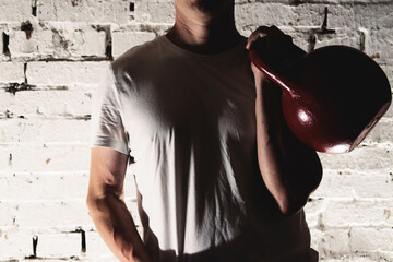 a young man in a white t-shirt holding a red kettlebell