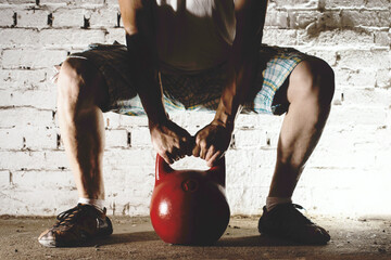 a man in a white t-shirt squats with a red kettlebell