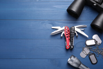Flat lay composition with compact portable multitool and accessories on blue wooden table. Space...