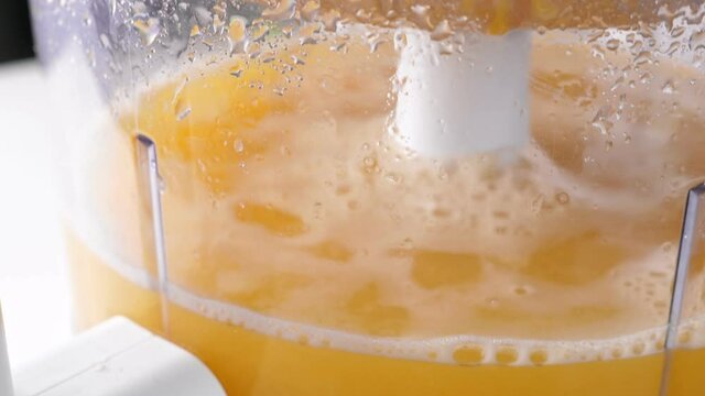 Preparing orange juice in juicer. Squeezing procces. Macro shot inside transparent bowl