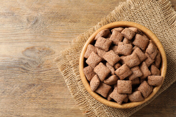 Sweet crispy corn pads in bowl on wooden table, top view. Space for text