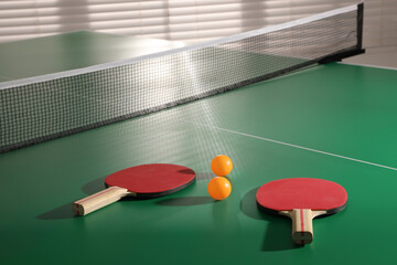 Rackets and balls on ping pong table indoors