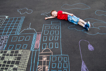 the child is lying on the asphalt. A city drawn in chalk on the asphalt
