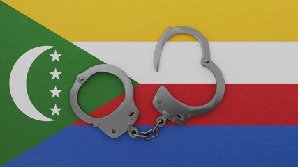 A half opened steel handcuff in center on top of the national flag of Comoros