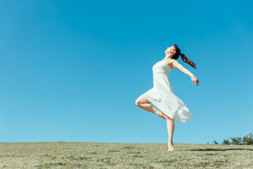 空と白いワンピースの踊る女性
