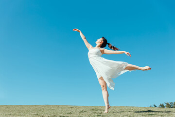 Obraz premium 空と白いワンピースの踊る女性（アラベスク） 