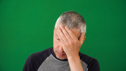 Fatigue in the human face. A mature adult man of European descent with gray hair on the green...