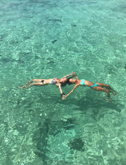 Beach travel. Girls floating and swimming in the crystal sea water. Caribbean Sea