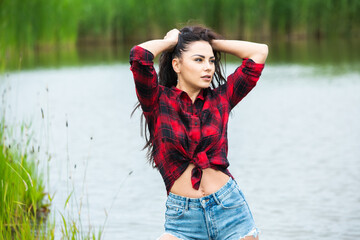 The brunette girl is having fun in the river in rubber boots in the country. Young woman on a lake...