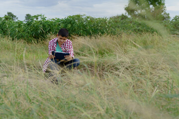 Naklejka na ściany i meble boy sitting on a tablet in the meadow,boy playing tablet in natural area