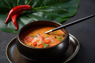 Tom Yam kung Spicy Thai soup with shrimps, coconut milk and chili pepper in bowl.
