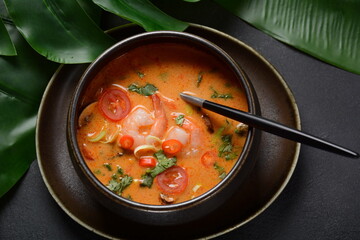 Tom Yam kung Spicy Thai soup with shrimps, coconut milk and chili pepper in bowl.
