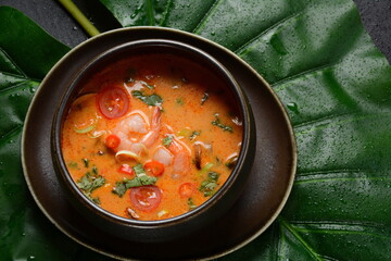 Tom Yam kung Spicy Thai soup with shrimps, coconut milk and chili pepper in bowl.