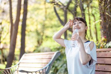 トレーニング中に休憩する女性（水を飲む・笑顔）
