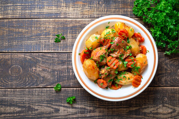 Roast turkey, potatoes, carrots and fresh parsley in a bowl on a wooden background. Top view. Copy space